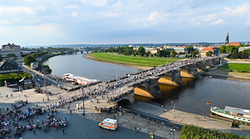 Teilnehmende an der Veranstaltung "Gastmahl für alle" sind auf der Augustusbrücke unterwegs. / Foto: Robert Michael/dpa