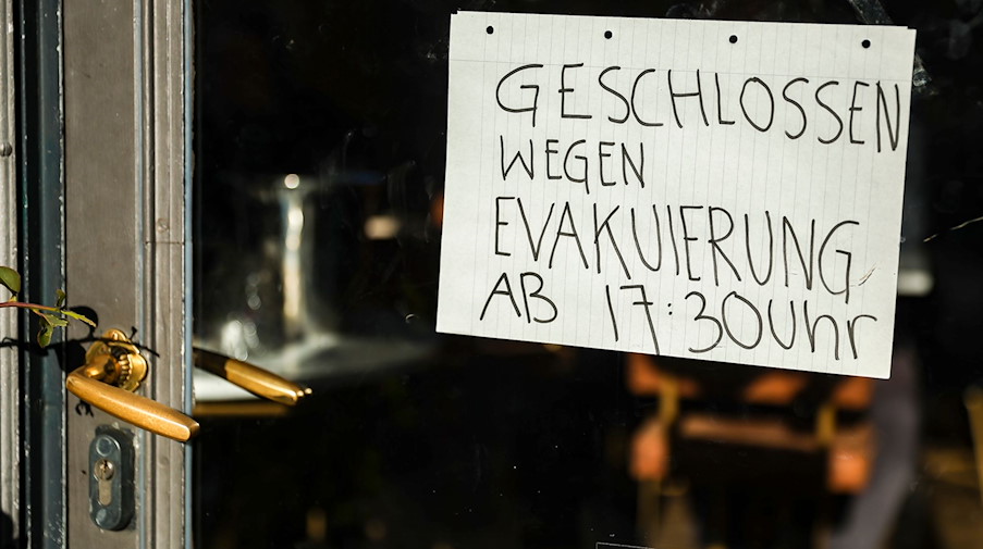 Ein Schild an einem Café weist darauf hin, dass wegen Evakuierung geschlossen wird. / Foto: Jan Woitas/dpa
