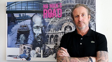 Autor und Regisseur Maik Große Lochtmann steht vor dem Filmplakat für "No Man's Road". / Foto: Roland Weihrauch/dpa