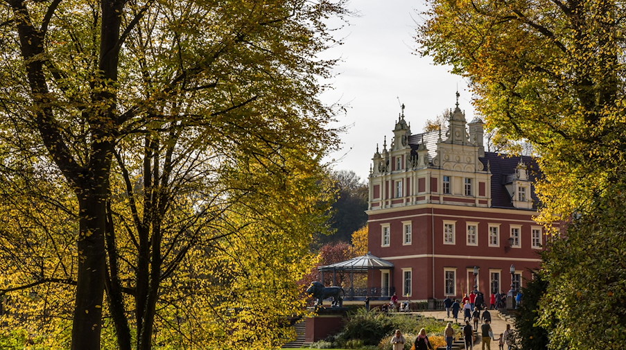 Spaziergänger sind bei sonnigem Herbstwetter am Neuen Schloss in Bad Muskau unterwegs. / Foto: Frank Hammerschmidt/dpa/Archivbild