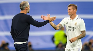 Trainer Marco Rose (l) und Reals Toni Kroos klatschen sich Spiel ab. / Foto: Jan Woitas/dpa/Archivbild