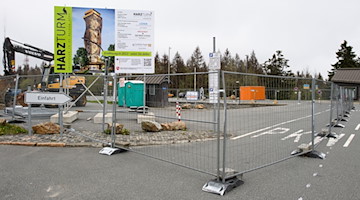 Ein Bauschild für den «Harzturm» ist auf einem Großraumparkplatz neben einem Bagger eingezäunt. / Foto: Swen Pförtner/dpa/Archivbild