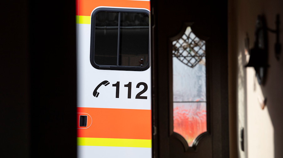 Ein Rettungswagen parkt vor der geöffneten Tür eines Wohnhauses. / Foto: Boris Roessler/dpa/Symbolbild