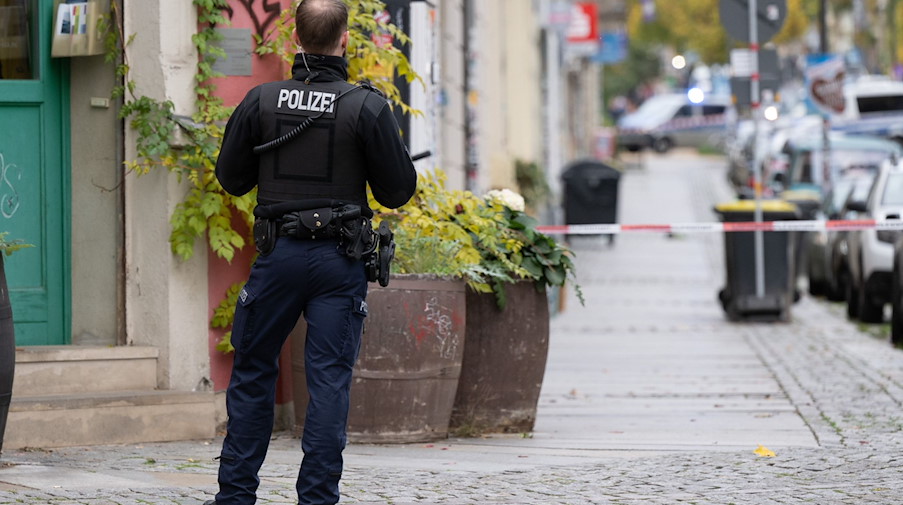 Ein Polizist steht im Stadtteil Leipziger Vorstadt auf der Rudolf-Leonhard-Straße vor einem Absperrband. / Foto: Sebastian Kahnert/dpa