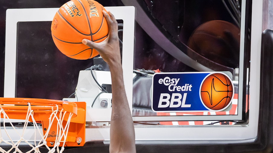 Ein Spieler dunkt, wobei das Logo der Basketball-Bundesliga BBL zu sehen ist. / Foto: Christoph Soeder/dpa