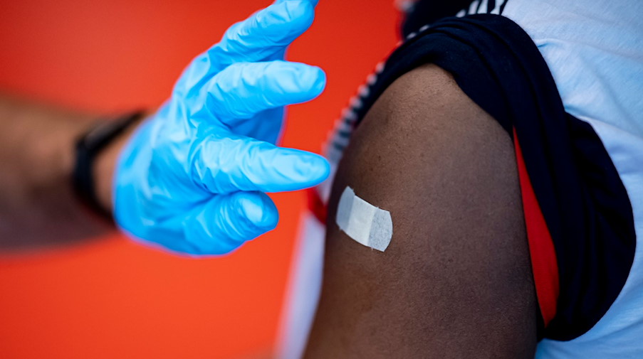 Ein Arzt klebt einer Frau nach der Impfung ein Pflaster auf den Oberarm. / Foto: Fabian Sommer/dpa/Symbolbild