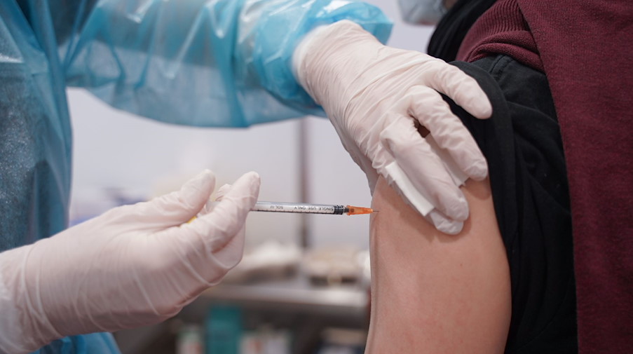 Ein Mitarbeiter eines Impfzentrums impft einen Mann gegen Corona. / Foto: Jörg Carstensen/dpa/Symbolbild