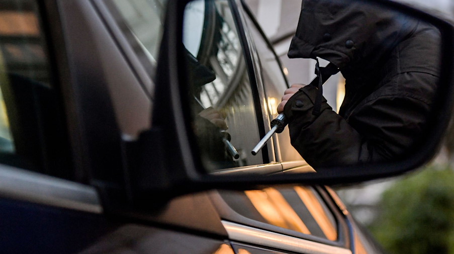 Ein Mann versucht eine Autotür mit einer Metallstange aufzubrechen (gestellte Szene). / Foto: Axel Heimken/dpa/Illustration