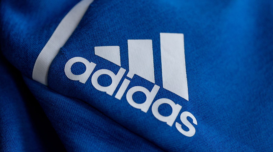 Das Logo des Sportartikelherstellers adidas auf einer blauen Jacke. / Foto: Daniel Karmann/dpa/Archiv