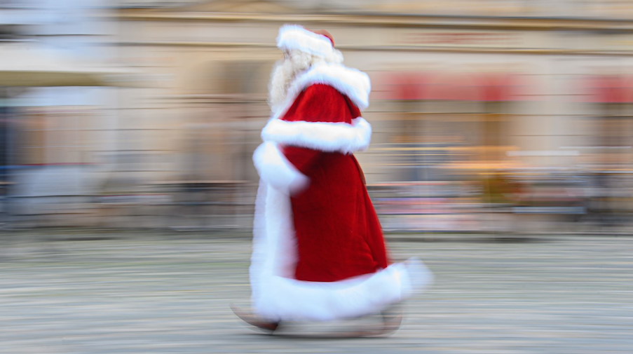 Ein Weihnachtsmann läuft über den Neumarkt. / Foto: Robert Michael/dpa-Zentralbild/dpa/Archivbild