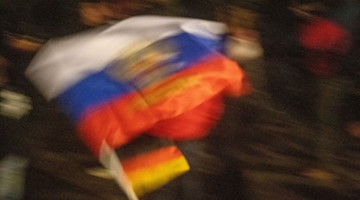 Eine Demonstrantin schwenkt eine russische und eine deutsche Flagge. / Foto: Stefan Sauer/dpa/Symbolbild