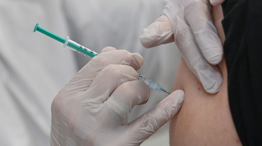 Ein Mitarbeiter eines Impfzentrums impft einen Mann gegen Corona. / Foto: Patrick Pleul/dpa-Zentralbild/dpa/Symbolbild