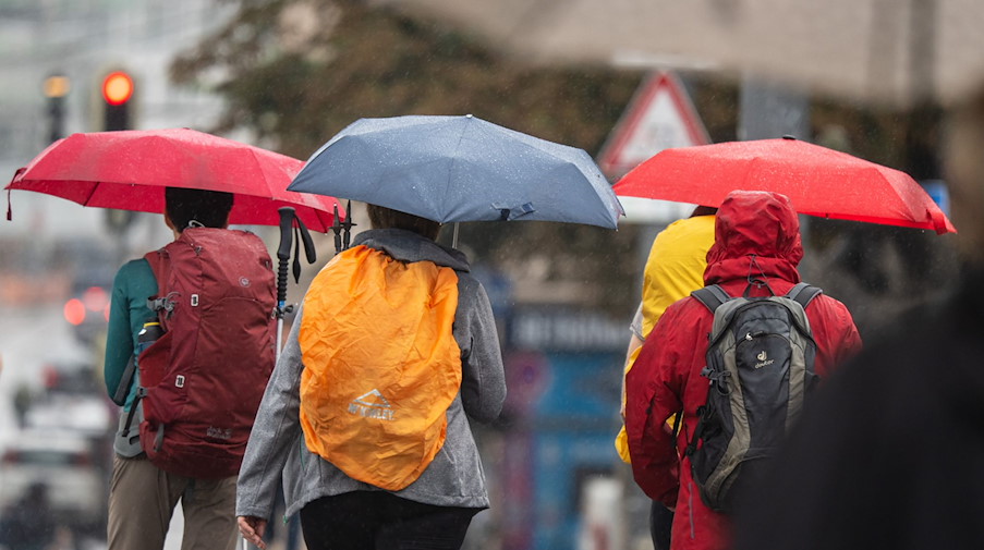 Menschen schützen sich bei Regen mit ihren Schirmen. / Foto: Peter Kneffel/dpa/Symbolbild