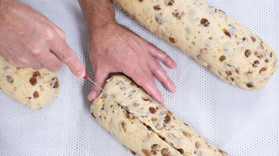 Tino Gierig, Bäckermeister, schneidet mit einem Messer einen geformten Christstollen. / Foto: Sebastian Kahnert/dpa