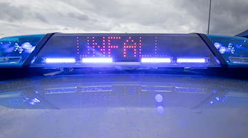 Ein Blaulicht und eine LED-Anzeige leuchten auf dem Dach eines Polizeifahrzeugs. / Foto: Daniel Karmann/dpa/Symbolbild