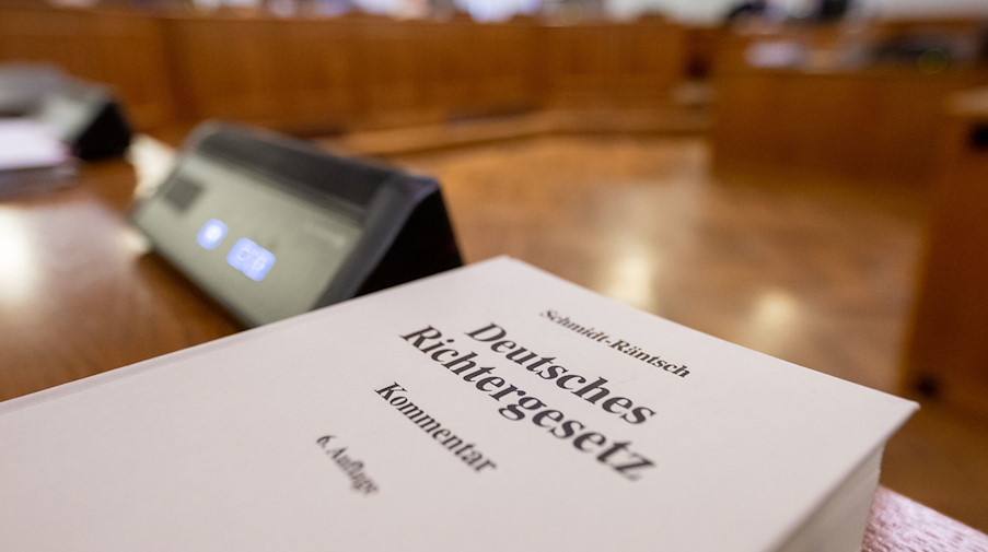 Eine Ausgabe des «Deutschen Richtergesetzes» liegt auf einem Tisch im Verhandlungssaal. / Foto: Hendrik Schmidt/dpa