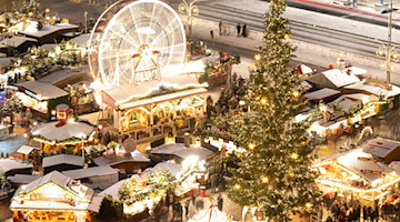 Ein Riesenrad dreht sich neben mit Schnee bedeckten Verkaufsständen auf dem Striezelmarkt (Aufnahme mit Langzeitbelichtung). / Foto: Sebastian Kahnert/dpa
