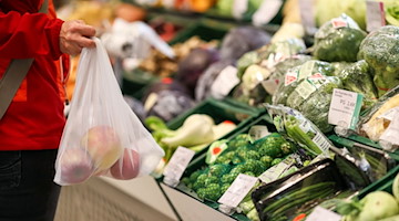 Eine Kundin steht mit einem Mehrweg-Einkaufsnetz in der Obst- und Gemüseabteilung in einem Supermarkt. / Foto: Jan Woitas/dpa-Zentralbild/dpa
