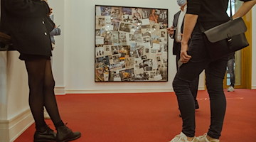 Teilnehmer an einer Presseveranstaltung stehen im Museum für Fotografie vor einer Collage über Helmut Newton. / Foto: Paul Zinken/dpa/Archivbild
