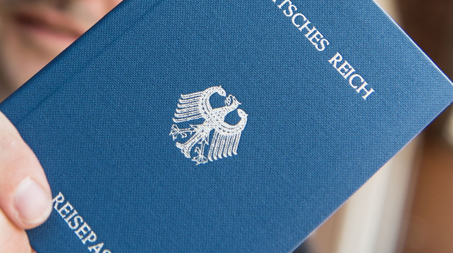 Ein Mann hält ein Heft mit dem Aufdruck «Deutsches Reich Reisepass» in der Hand. / Foto: Patrick Seeger/dpa/Illustration