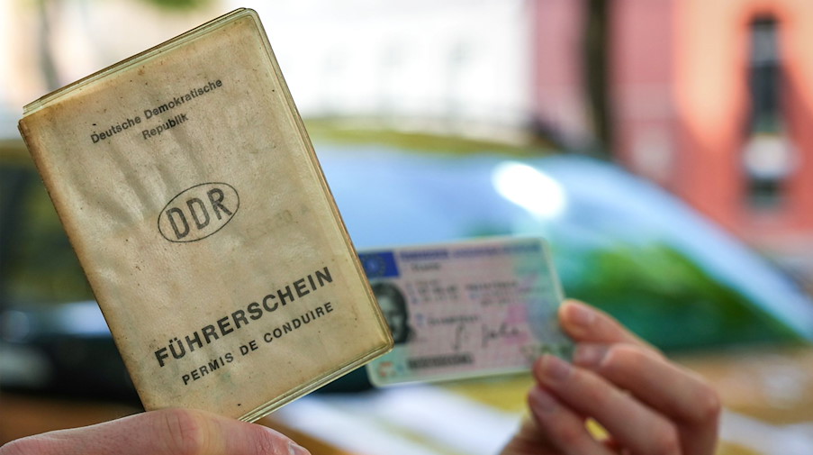 Ein Mann hält seinen noch gültigen DDR-Führerschein und den Europäischen Führerschein im Scheckkartenformat in den Händen. / Foto: Soeren Stache/dpa/Archivbild