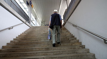 Ein älterer Mann mit Gehstock geht auf einer Treppe in einer Bahnhofsunterführung. / Foto: picture alliance/dpa/Symbolbild