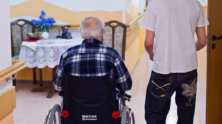 Im einem Seniorenheim betreut ein junger Mann einen Mann im Rollstuhl. / Foto: Patrick Pleul/dpa-Zentralbild/dpa/Archivbild