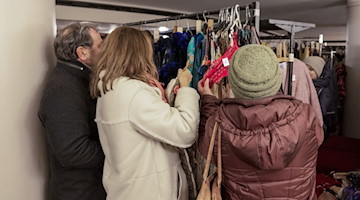 Ein Mann und zwei Frauen schauen sich im Foyer der Semperoper das Angebot beim Kostümverkauf an. / Foto: Daniel Schäfer/dpa