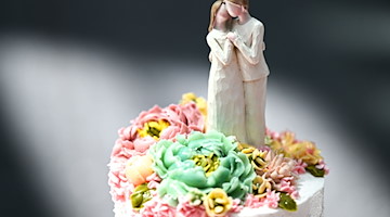 Eine Figur, die einen Mann und eine Frau darstellt, steht auf einer Hochzeitstorte. / Foto: Felix Kästle/dpa/Symbolbild