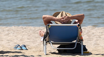 Ein Mann liegt am Strand in einem Liegestuhl. / Foto: Sebastian Kahnert/dpa-Zentralbild/dpa/Symbolbild