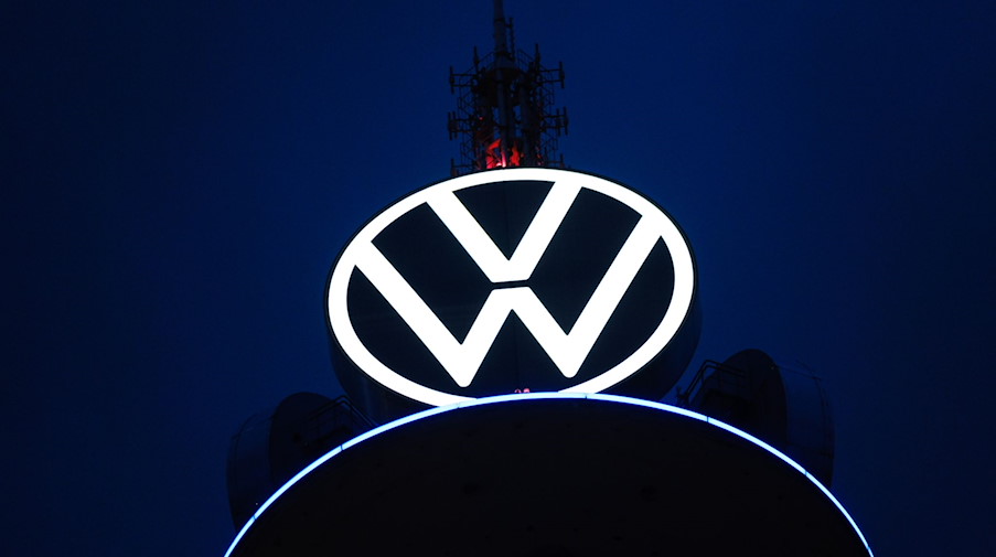 Das Volkswagen Logo leuchtet auf dem VW-Tower vor dunklem Himmel. / Foto: Ole Spata/dpa/Archivbild