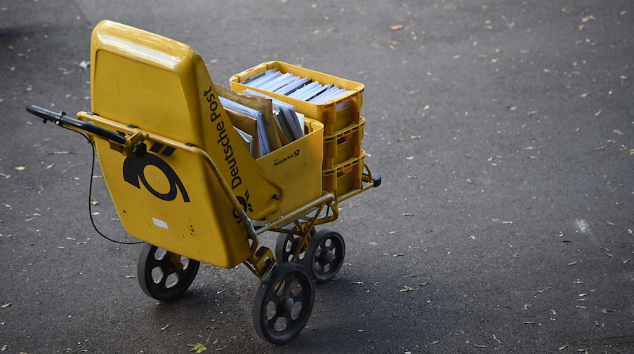 Ein Trolley eines Zustellers der Deutschen Post steht auf der Straße. / Foto: Lino Marcel Mirgeler/dpa/Illustration