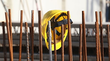 Ein Bauhelm hängt an Fundament-Stangen auf einer Baustelle. / Foto: Bodo Schackow/dpa-Zentralbild/dpa/Symbolbild