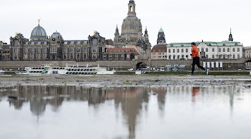 Ein Läufer am Ufer der Elbe vor der Kulisse der Altstadt. / Foto: Sebastian Kahnert/dpa