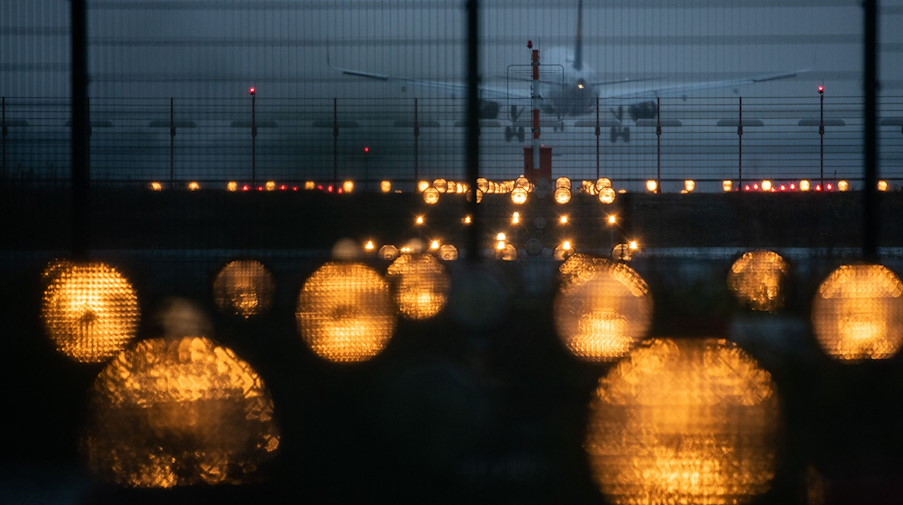 Ein Flugzeug landet hinter Signallichtern auf einem Flughafen. / Foto: Sebastian Gollnow/dpa/Symbolbild