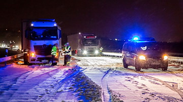 Lastwagen stehen im Schnee auf der Autobahn 72 (A72) neben einem Fahrzeug der Polizei. / Foto: Andre März/dpa/Archivbild