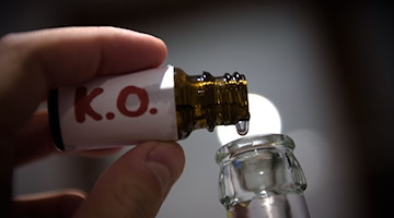 K.O.-Tropfen werden in einer gestellten Szene in eine Bierflasche gefüllt. / Foto: Nicolas Armer/dpa/Illustration