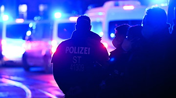 Polizisten stehen bei einem Einsatz auf der Straße. / Foto: Hendrik Schmidt/dpa/Symbolbild