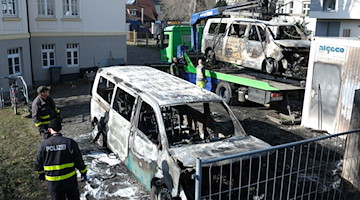 Ausgebrannte Fahrzeuge vom Staatsbetrieb Sachsenforst werden von der Polizei gesichert. / Foto: Sebastian Willnow/dpa