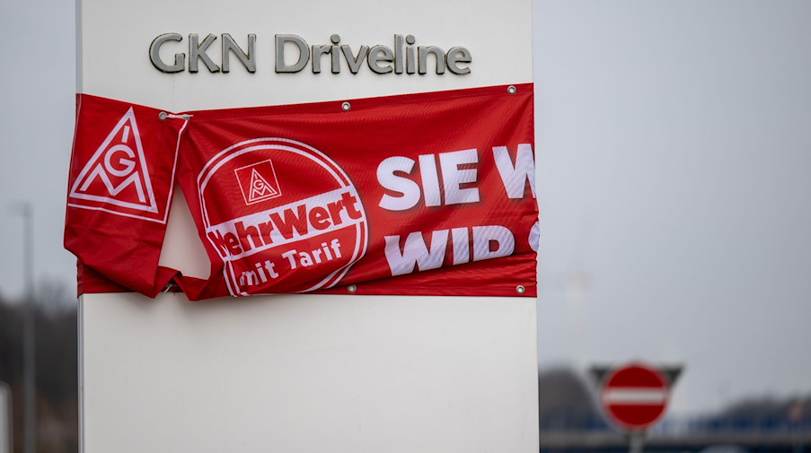 Ein Banner mit der Aufschrift «MehrWert mit Tarif» hängt am Eingang zum Gelenkwellenwerk Mosel. / Foto: Hendrik Schmidt/dpa