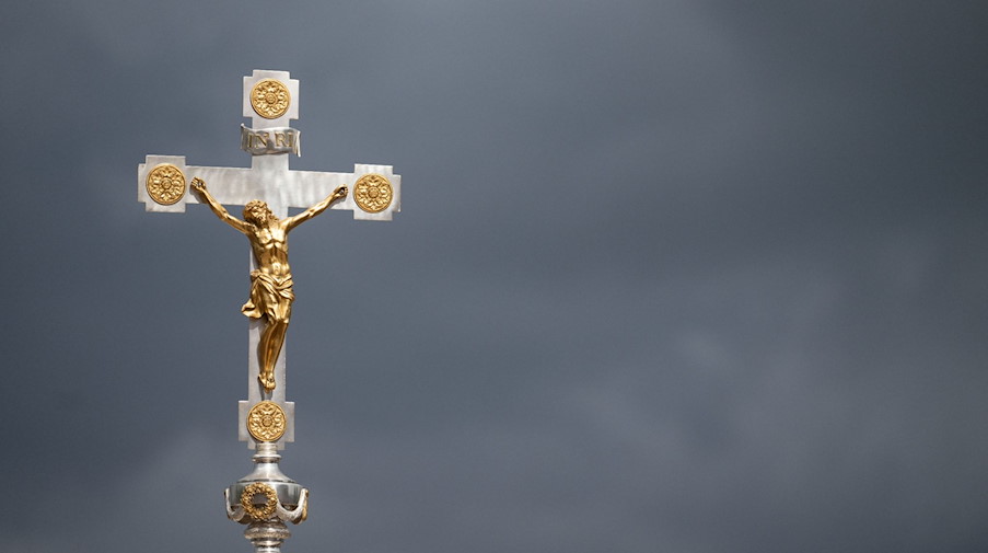 Ein katholisches Kruzifix ist vor dunklen Wolken zu sehen. / Foto: Marijan Murat/dpa/Symbolbild