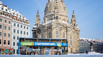 Blauer Doppeldeckerbus der Stadtrundfahrt Dresden vor der Dresdner Frauenkirche im Winter
