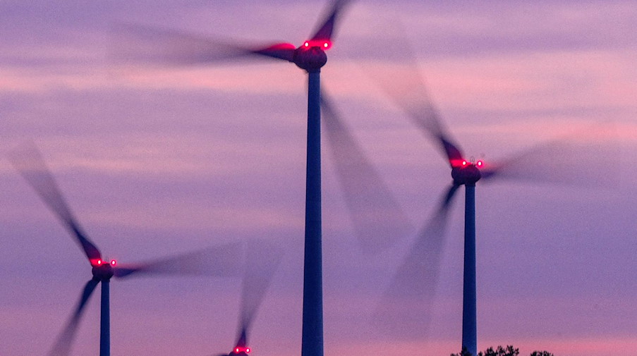 Mit Signallampen beleuchtete Windräder drehen sich nach Sonnenuntergang. / Foto: Jens Büttner/dpa/Archivbild