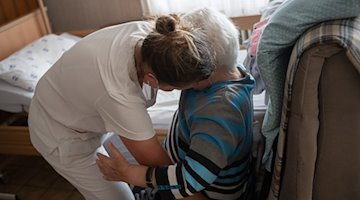 Eine Pflegefachkraft hilft in der ambulanten Pflege einer Frau beim Umsetzen. / Foto: Sebastian Gollnow/dpa/Symbolbild
