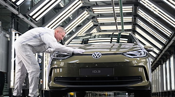 Rainer Jopp, Meister in der Fahrzeug Endabnahme in der Gläsernen Manufaktur, präsentiert ein E-Auto. / Foto: Robert Michael/dpa