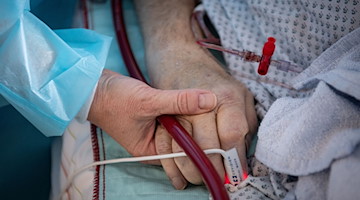 Eine Krankenschwester versorgt einen Patienten. / Foto: Boris Roessler/dpa/Symbolbild