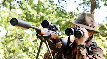 Jägerin Cynthia schaut neben ihrem Gewehr durch ein Fernrohr, bevor sie auf Jagd in ihrem Revier geht. / Foto: Waltraud Grubitzsch/dpa-Zentralbild/dpa/Archivbild