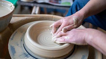 An artist shapes a vase with her hands at the potter's wheel / Photo: Philipp Schulze/dpa/Symbolbild