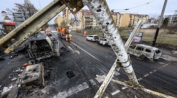 Ausgebrannte Autos stehen nach einem Brand an einer Gasleitung im Stadtteil Friedrichstadt am Straßenrand. / Foto: Robert Michael/dpa/Archivbild