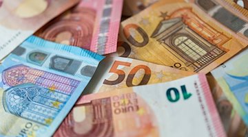Zahlreiche Banknoten von 10, 20 und 50 Euro liegen auf einem Tisch. / Foto: Monika Skolimowska/dpa-Zentralbild/dpa/Illustration